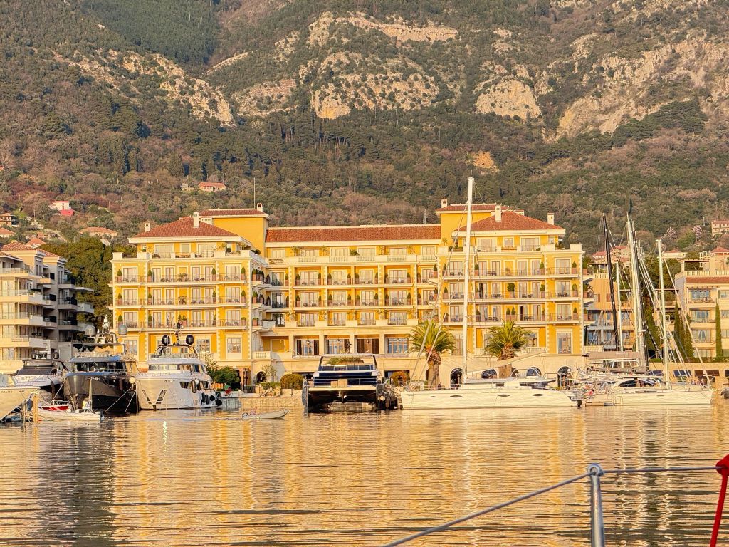 Large yachts and luxury condos with the backdrop of high mountains
